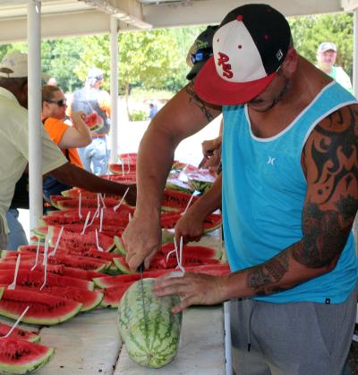A volunteer cuts through a locally grown watermelon at the 2016 Rush Springs Watermelon Festival. Hundreds of pounds of watermelon are consumed under the awnings at Jeff Davis Park. HMG file photo
