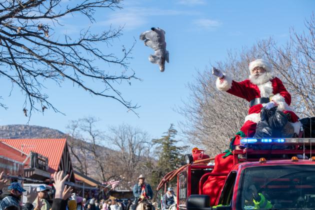 Santa throws a stuffed animal to children at the 2021 Medicine Park Christmas parade.