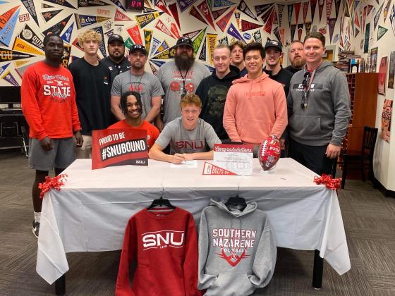 Toby Parker, seated center, signs a letter of intent to play college football at Southern Nazarene University next season. Parker started at cornerback for the Elgin Owls in 2022. Standing behind Parker are Elgin teammates and coaches. PHOTO PROVIDED