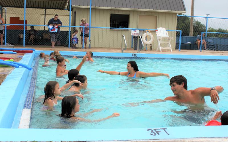 Lifeguards Rylen Lemons and Dylan Burk, both students at the University of Oklahoma, teach a group of older swimmers to swim above water.