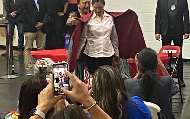 The audience watches as Delores Twohatchet, a Kiowa and Comanche woman, wraps a handmade shawl around Secretary of the Interior Deb Haaland July 11 at Riverside Indian School in Anadarko. Twohatchet and other survivors of the federal Indian boarding school system shared their stories during the first stop on the Interior Department’s “Road to Healing” tour.  Eric Swanson/Staff photo
