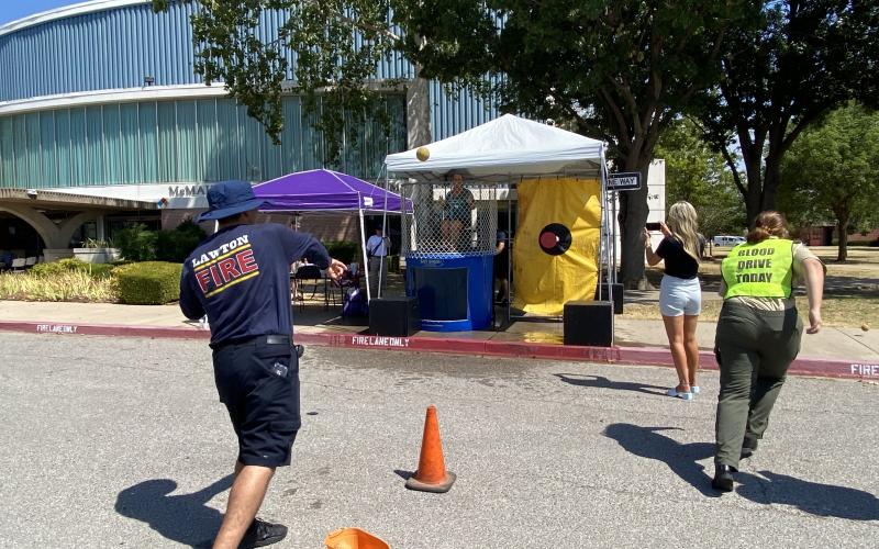 Corporal Stiven Jimenez, Lawton Fire Department, throws ball at the dunk tank where Dr. Krista Ratliff, president and CEO of Lawton-Fort Sill Chamber of Commerce, awaits the splash. Photos by Curtis Awbrey