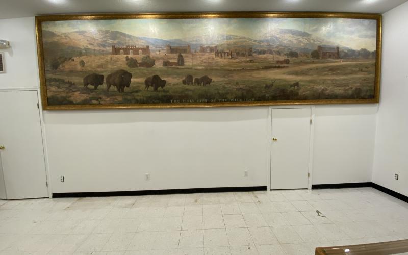 Paul Frable, board president for Holy City of the Wichitas, points out different structures on the recently restored mural. The mural was found in a damp museum storage room in 2017. Photo by Curtis Awbrey