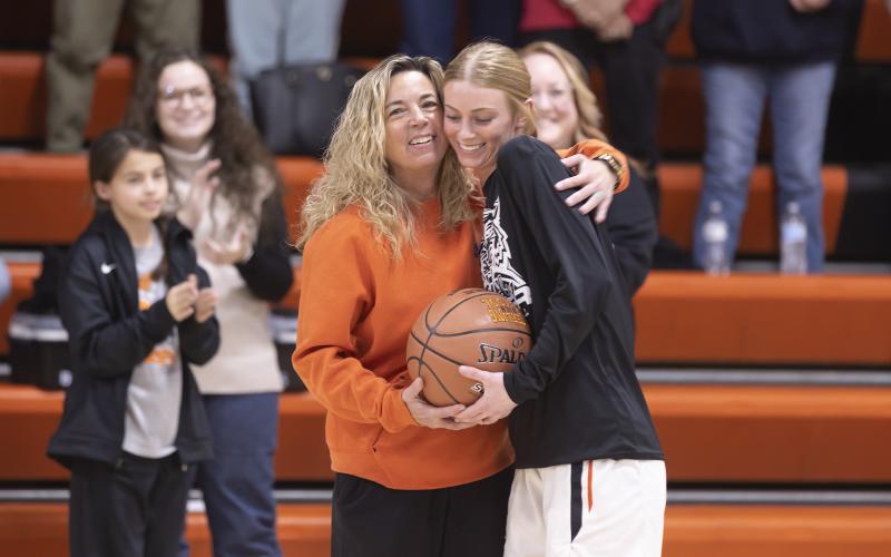 Hugh Scott Jr. | swchronicle Sports Sterling senior Emma Nunley, right, accepts a hug from her coach Jennifer Garner as the home crowd cheers her milestone of scoring 1,000 points during her high school career. Nunley was presented with a professionally stitched ball that reads, “Emma Nunley, 1,000 career points, 2023.”