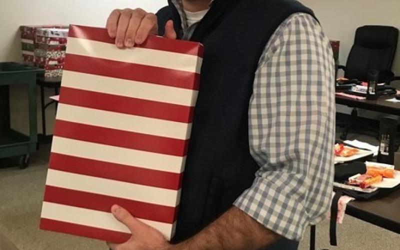 District Supervisor Jaremy Andrews for the Office of Juvenile Affairs displays a gift box he finished packing for one of more than 200 youths in OJA custody. The gifts were purchased with funds provided by the Santa Claus Commission. OFFICE OF JUVENILE AFFAIRS