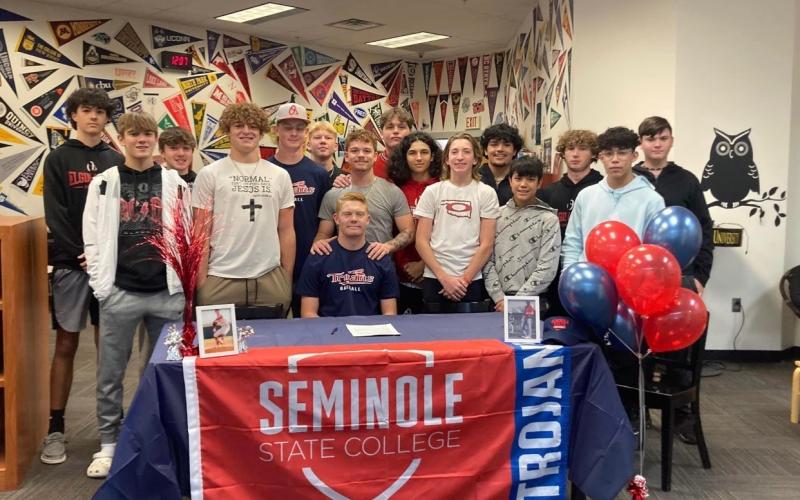 Surrounded by teammates, Elgin baseball player Jake Thomas signs a letter of intent to play for Seminole State College next season. The ceremony was held Wednesday at the Elgin High School library. PHOTO PROVIDED