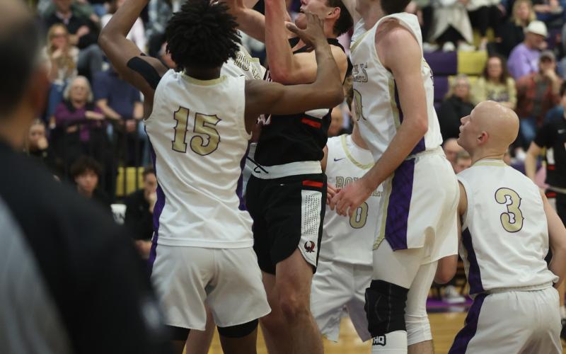 Elgin's Christian Reed tries to shoot the ball while surrounded by Community Christian defenders Friday night. Reed finished with 12 points as the Owls won their sixth district championship in seven years. (Photo by Hugh Scott Jr.)