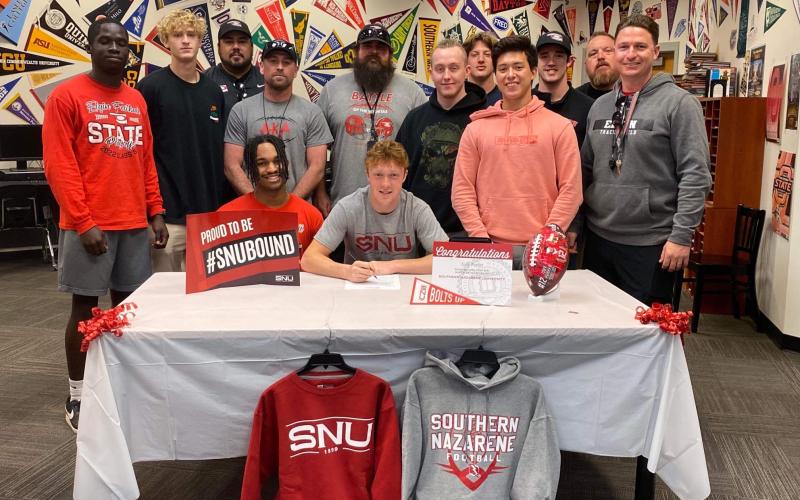 Toby Parker, seated center, signs a letter of intent to play college football at Southern Nazarene University next season. Parker started at cornerback for the Elgin Owls in 2022. Standing behind Parker are Elgin teammates and coaches. PHOTO PROVIDED