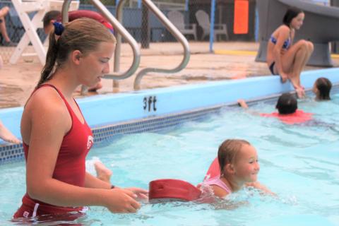 Rachel Gregg, high school lifeguard, watches as Brynlee Sanders of Cyril, age 4, uses a flotation device to swim the width of the pool.