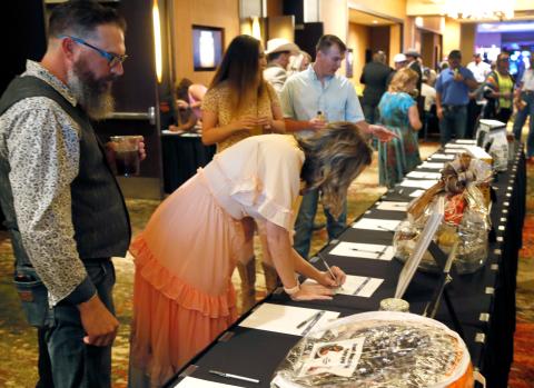 Dr. Holly Lunsford and her husband Brian sign up for a silent auction item at the Saddle & Sirloin Club's dinner and live auction on July 16th in Lawton Rip Still/Ledger
